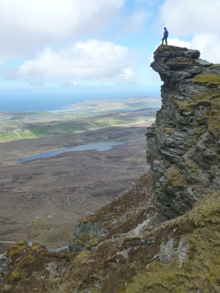 Person standing on top of rocks overlooking valley.
